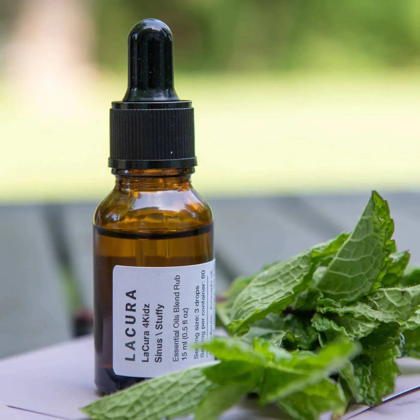 Bottle of Lacura 4KHz with a dropper on a surface with green leaves in the foreground